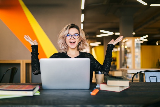 funny-happy-excited-young-pretty-woman-sitting-table-black-shirt-working-laptop-co-working-office-wearing-glasses_285396-86